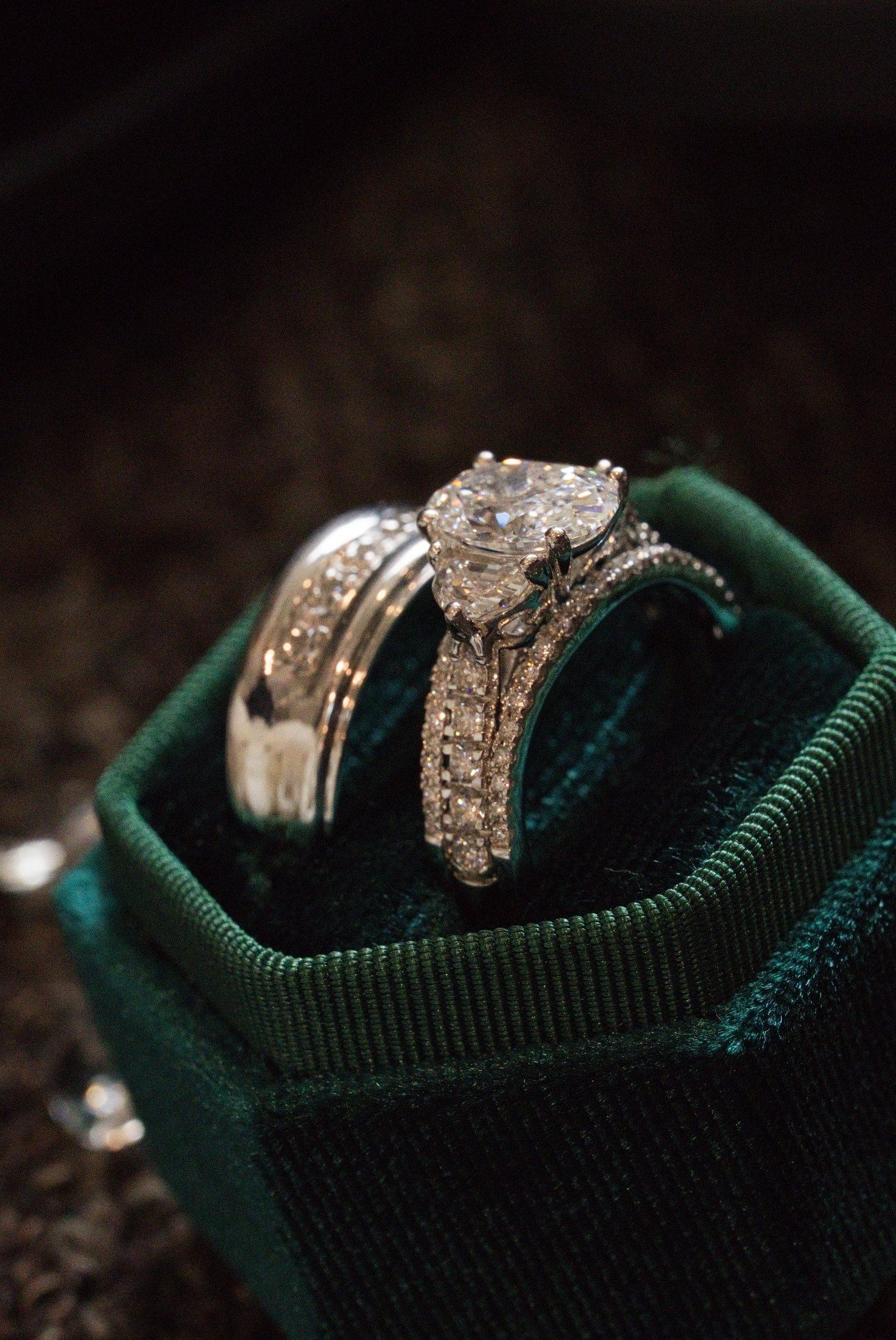 The couple's wedding and engagement rings arranged on deep green velvet