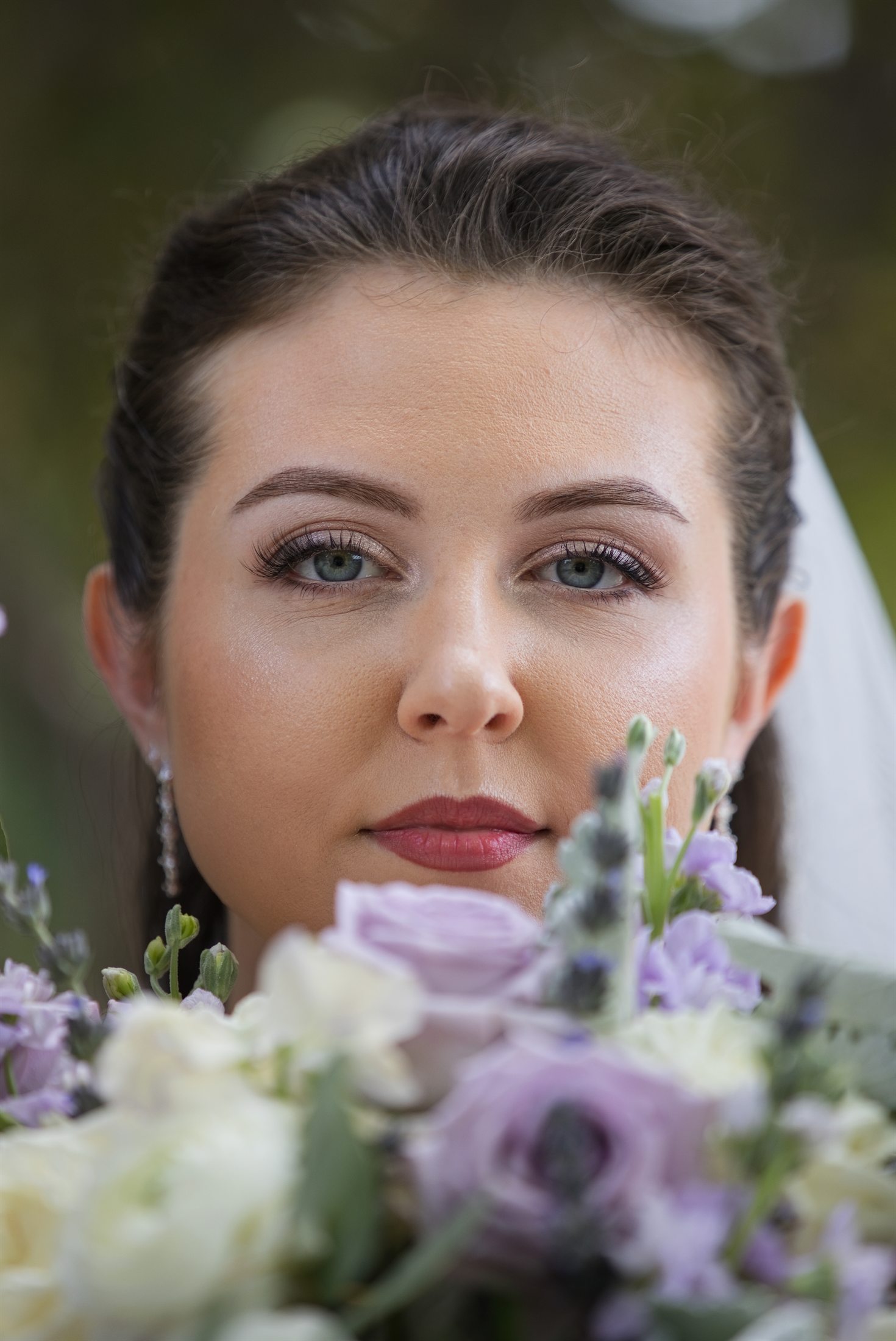 A close bridal portrait framed by lavender and white flowers