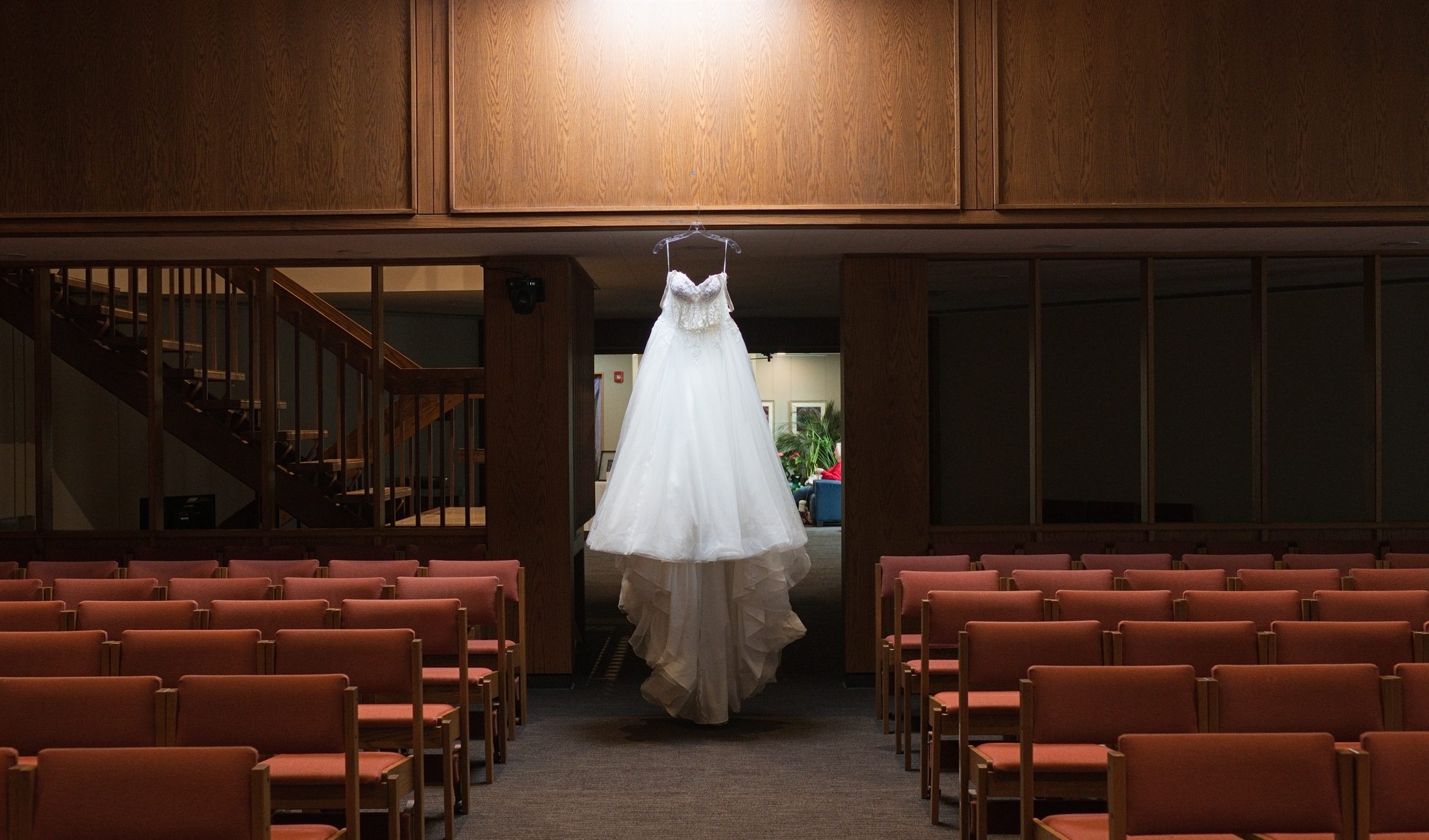 A wedding dress hanging above the ceremony aisle