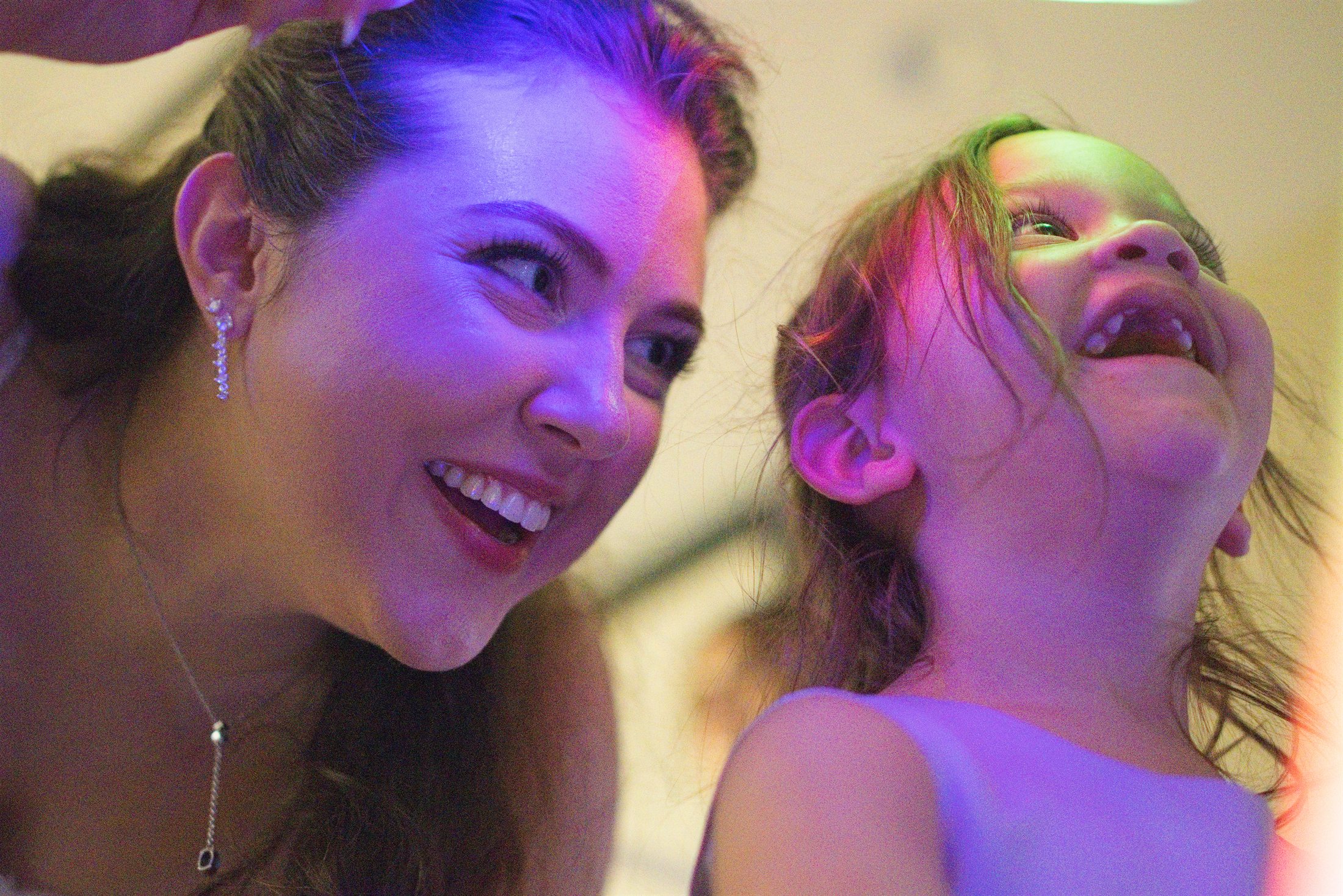 The bride sharing a joyful moment with a young guest under colorful reception lights